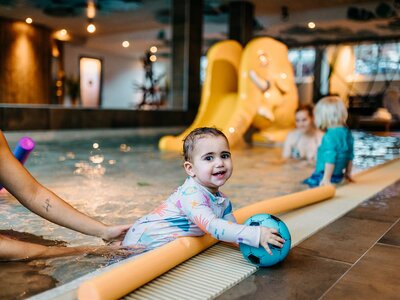 Baby spielt mit Ball im Babybecken