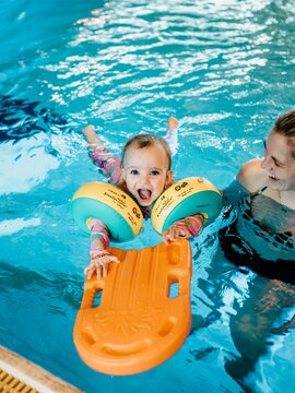 Kleinknd mit Schwimmflügeln und Schwimmnudel