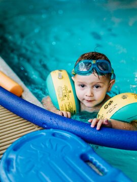 Kleinknd mit Schwimmflügeln und Schwimmnudel