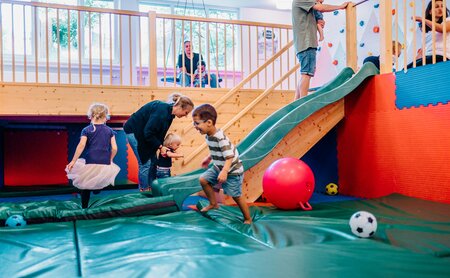 Kleinkinder rutschen im Toberaum