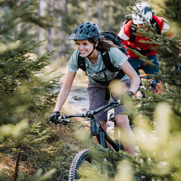 Frau beim Mountainbiken durch den Wald