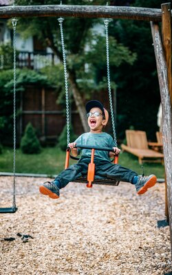 Junge schaukelt auf der Schaukel vom Spielplatz