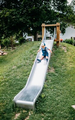 Junge rutscht auf der Rutsche am Spielplatz