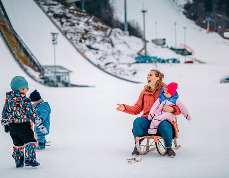 Kinder spielen auf Rodel im Schnee